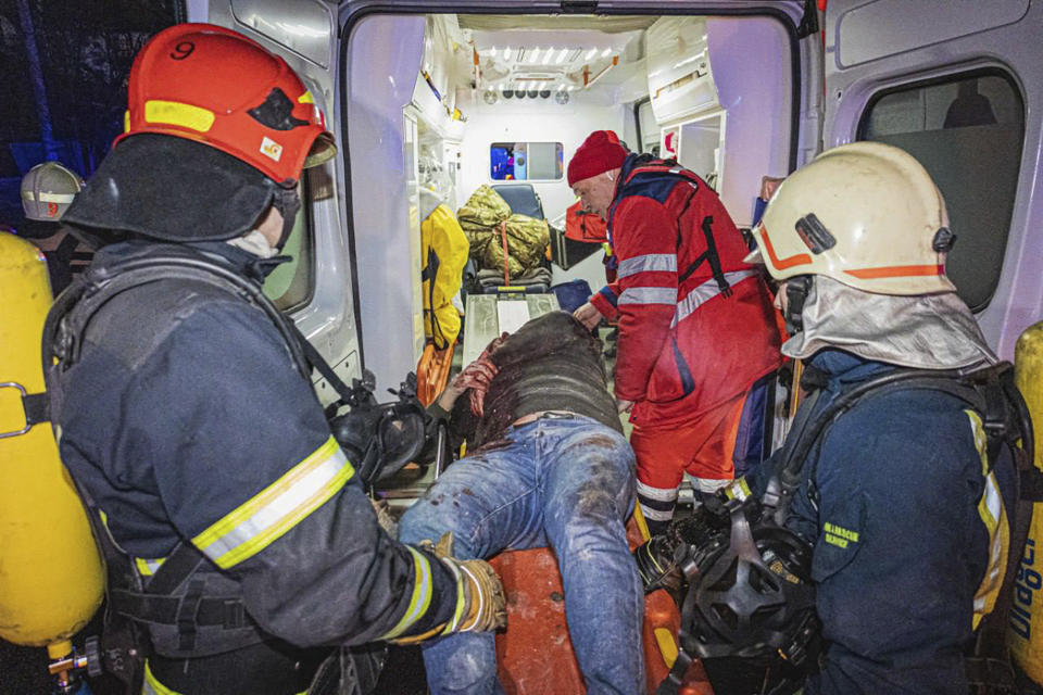 En esta imagen proporcionada por el Servicio Ucraniano de Emergencias, bomberos y paramédicos prestan primeros auxilios a un hombre herido en un ataque de misiles rusos contra un hotel en Járkiv, Ucrania, la noche del martes 10 de enero de 2024. (Servicio Ucraniano de Emergencias via AP)