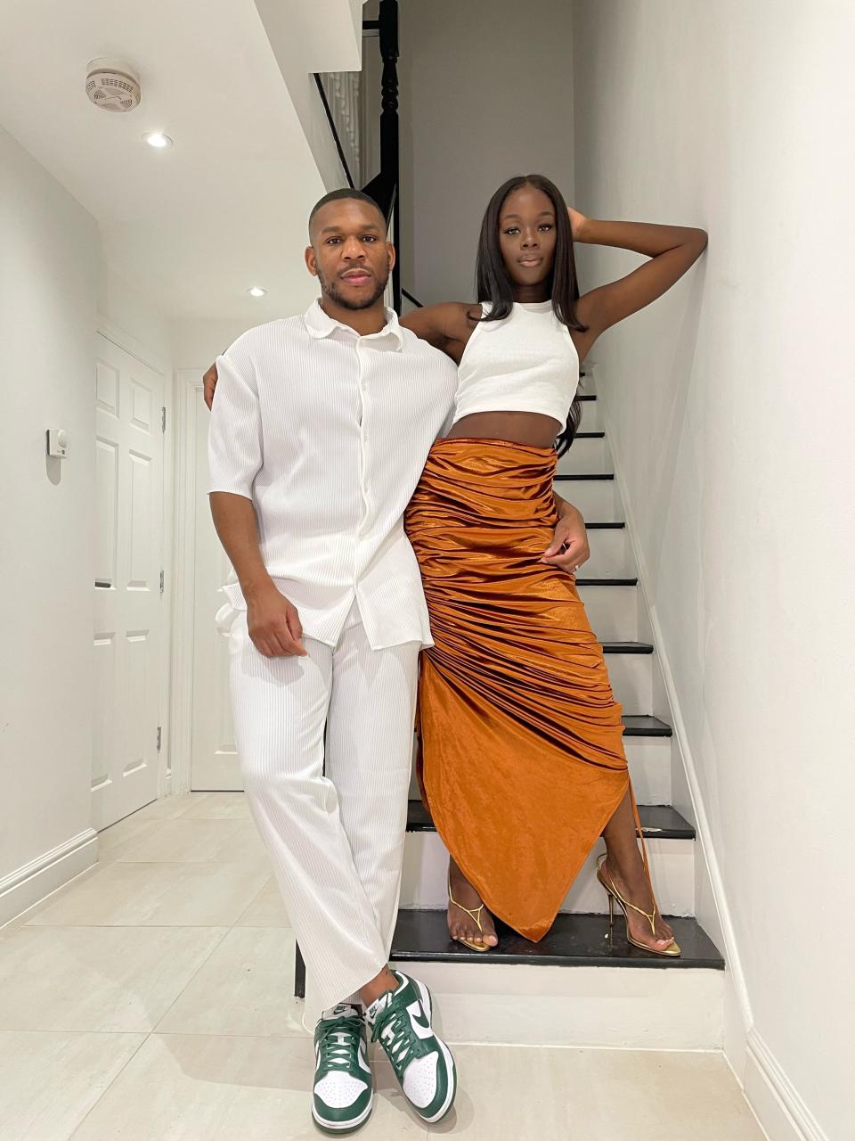 A man and a woman pose on a staircase.