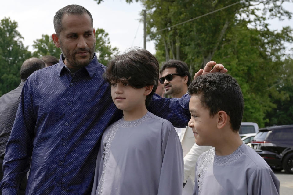 Nasrat Ahmad Yar's sons Asem Ahmad Yar, 8, right, and Wahdad Ahmad Yar, 10, center, are comforted by Rahim Amini, a friend of their fathers, during a funeral service for their father at the All Muslim Association of America cemetery on Saturday, July 8, 2023, in Fredericksburg, Va. Ahmad Yar, an Afghan immigrant who worked as an interpreter for the U.S. military in Afghanistan, was shot and killed on Monday, July 3, while working as a ride-share driver in Washington. (AP Photo/Mariam Zuhaib)