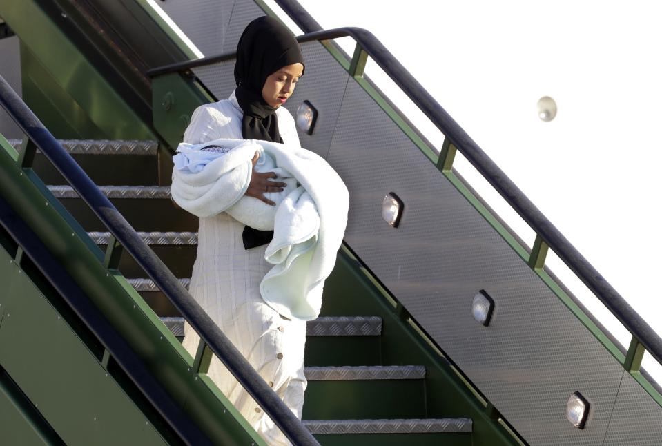 A woman holds a baby as she disembarks an Italian military aircraft arriving from Misrata, Libya, at Pratica di Mare military airport, near Rome, Monday, April 29, 2019. Italy organized a humanitarian evacuation airlift for a group of 147 asylum seekers from Ethiopia, Eritrea, Somalia, Sudan and Syria. (AP Photo/Andrew Medichini)