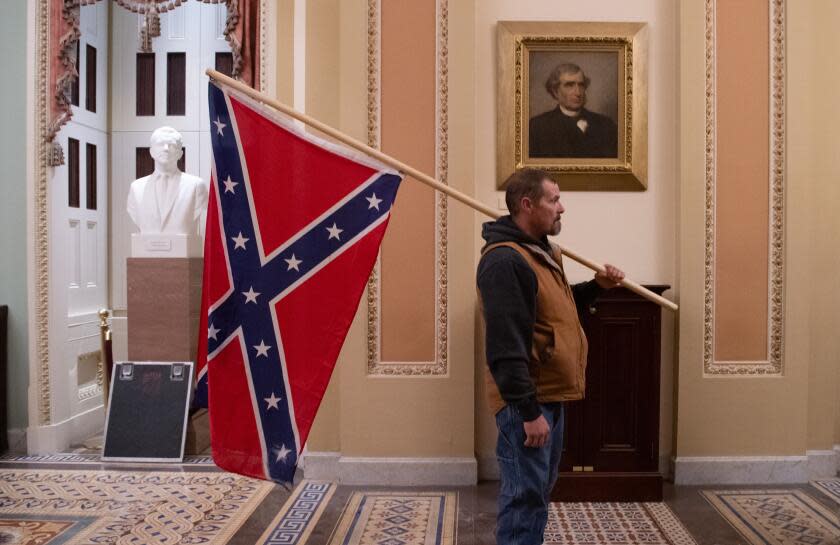 (FILES) A supporter of US President Donald Trump holds a Confederate flag outside the Senate Chamber during a protest after breaching the US Capitol in Washington, DC, January 6, 2021. - The demonstrators breeched security and entered the Capitol as Congress debated the 2020 presidential election Electoral Vote Certification. (Photo by SAUL LOEB / AFP) (Photo by SAUL LOEB/AFP via Getty Images)