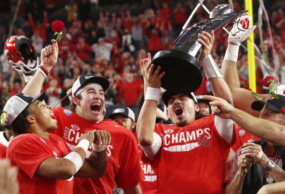 Utah quarterback Cameron Rising, right, holds up the trophy and celebrates with Dalton Kincaid, center, and Micah Bernard after Utah defeated Southern California 47-24 in the Pac-12 Conference championship NCAA college football game Friday, Dec. 2, 2022, in Las Vegas. | Steve Marcus, Associated Press