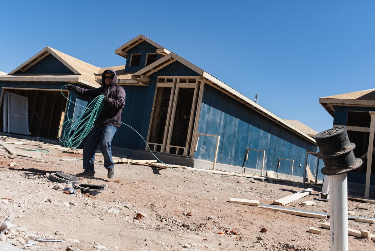 A construction worker, who declined to give their name, rolls up hosing as they work on building a home at a new housing development Saturday, March 12, 2022 in Odessa, Texas.