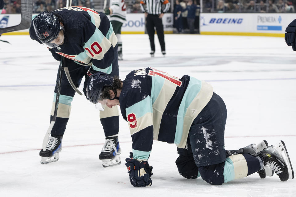 Seattle Kraken forward Matty Beniers, left, checks on forward Jared McCann, right, during a break in the action in the first period of an NHL hockey game against the Minnesota Wild, Saturday, Feb. 24, 2024, in Seattle. (AP Photo/Stephen Brashear)