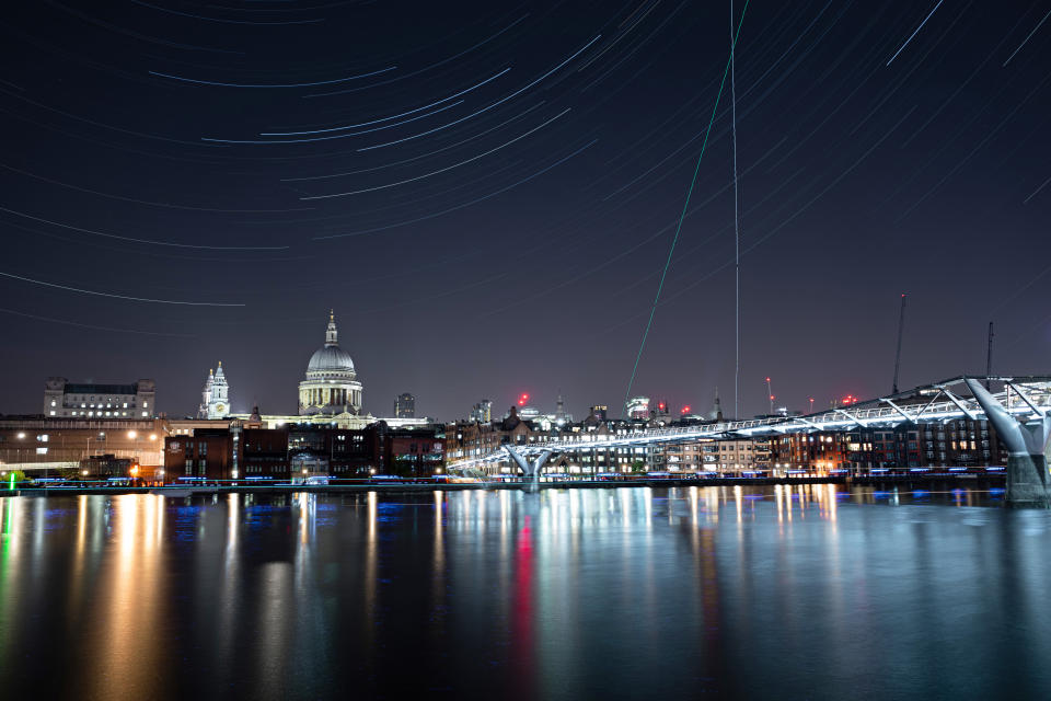 The Millennium Bridge is illuminated under the stars on a clear night in London, England.