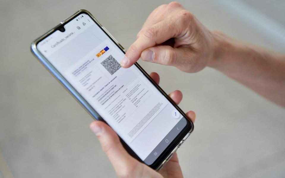 A woman checks her EU Digital Covid certificate on her mobilephone at El Prat airport in Barcelona on July 1 - PAU BARRENA/AFP via Getty Images