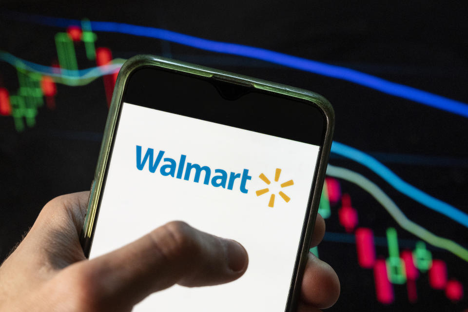 CHINA - 2021/12/09: In this photo illustration the American multinational department stores Walmart logo seen displayed on a smartphone with an economic stock exchange index graph in the background. (Photo Illustration by Budrul Chukrut/SOPA Images/LightRocket via Getty Images)