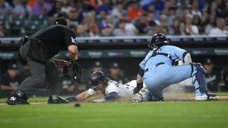Detroit Tigers' Zach McKinstry (39) dives to score ahead of the tag of Toronto Blue Jays catcher Danny Jansen (9) as home plate umpire Jeremy Riggs, left, looks on in the eighth inning of a baseball game, Friday, July 7, 2023, in Detroit. (AP Photo/Paul Sancya)