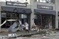 A woman walks past buildings damaged by storms Tuesday, March 3, 2020, in Nashville, Tenn. Tornadoes ripped across Tennessee early Tuesday, shredding buildings and killing multiple people. (AP Photo/Mark Humphrey)