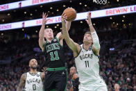 Boston Celtics guard Payton Pritchard, frontn left, and Milwaukee Bucks center Brook Lopez reach for the ball during the first half of an NBA basketball game Wednesday, March 20, 2024, in Boston. Bucks guard Damian Lillard is at left. (AP Photo/Steven Senne)