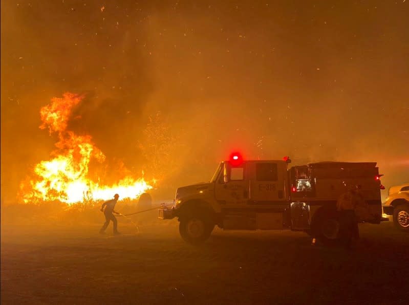 Firefighters battle flames along a highway during the Cave fire in Los Padres National Forest