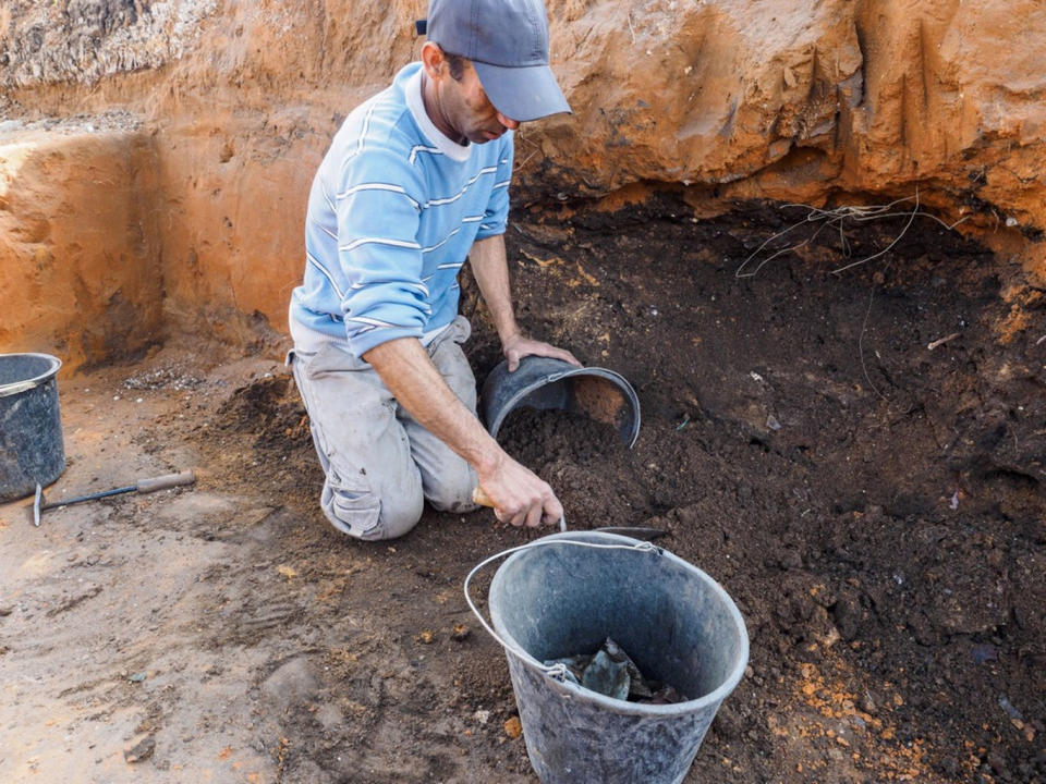 Archaeologist Ron Toueg collects artifacts from a pit near Ramla in Israel. <cite>Assaf Peretz/Israel Antiquities Authority</cite>