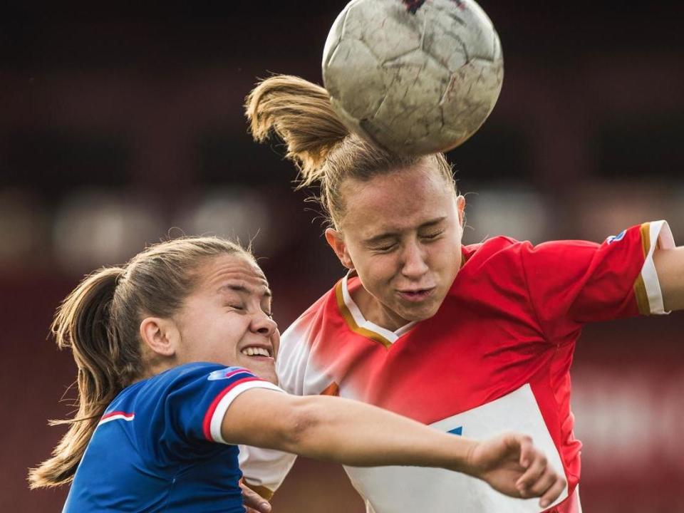 Determined teenage soccer players heading the ball on a match with their eyes closed: Getty