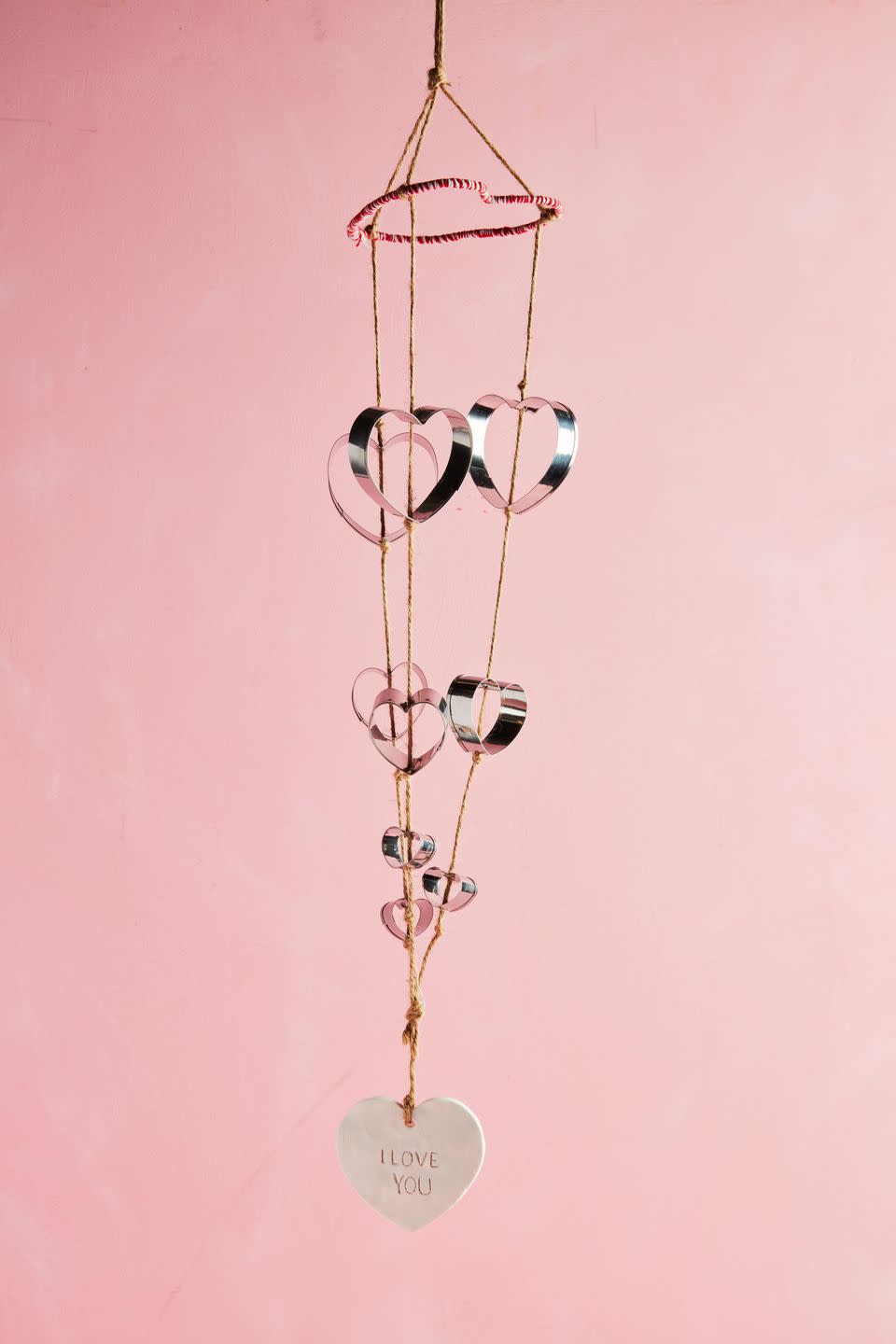 <p>Transform humble cookie cutters into cheery wind chimes that are ideal for hanging above a bed or on the front porch.<strong><br></strong></p><p><strong>To make:</strong> Fashion a 10- to 12-inch length of wire into a heart shape; wrap with red twine, set aside. Make a clay heart with <a href="https://www.amazon.com/POZEAN-Modeling-Sculpting-Accessories-Beginners/dp/B07XXWXBDP/ref=sr_1_1_sspa" rel="nofollow noopener" target="_blank" data-ylk="slk:oven-baked modeling clay;elm:context_link;itc:0;sec:content-canvas" class="link ">oven-baked modeling clay</a>; punch a hole in the top for hanging and write a phrase (if desired) before baking, and set aside. Punch holes in the crook and point of 3 large, 3 medium, and 3 small heart-shaped cookie cutters. Cut three lengths of twine. Working with one length at a time, thread a large, medium, and small cookie cutter onto twine, knotting above and below each cutter so that it stays in place. Repeat with remaining twine and cookie cutters. Wrap twine lengths (making sure the hearts are facing the correct direction) around wire heart; gather twine lengths at the top and tie in a knot for hanging. Knot twine lengths at the bottom and trim. Thread a short length of twine through the ceramic heart and tie to knot at the bottom of the wine chime, and hang.</p><p><a class="link " href="https://www.amazon.com/Ann-Clark-Cookie-Cutters-5-Piece/dp/B07ZDHJDKJ/ref=sr_1_4_sspa?tag=syn-yahoo-20&ascsubtag=%5Bartid%7C10050.g.2971%5Bsrc%7Cyahoo-us" rel="nofollow noopener" target="_blank" data-ylk="slk:SHOP COOKIE CUTTERS;elm:context_link;itc:0;sec:content-canvas">SHOP COOKIE CUTTERS</a></p>