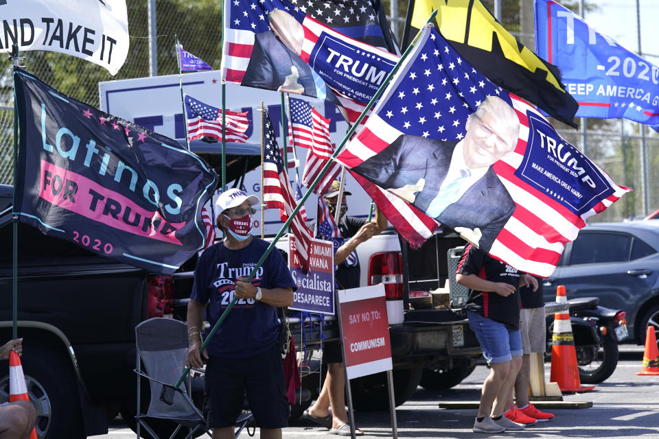 Orlando Bacallao carries a banner featuring President Donald Trump outside of an early voting location at the John F. Kennedy Library, Tuesday, Oct. 27, 2020, in Hialeah, Fla. (Lynne Sladky/AP)