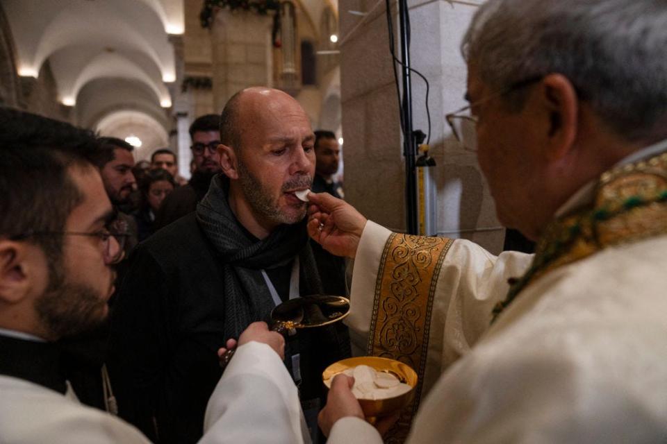 A Latin bishop gives holy bread to a worshiper during the Christmas midnight Mass at the Church of the Nativity in Bethlehem
