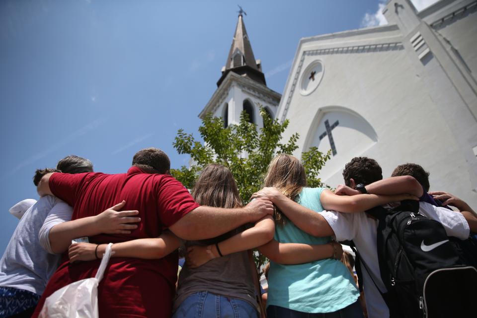 A church youth group from Dothan, Ala., prays in front of the Emanuel AME Church in July 2015, a month after a mass shooting in Charleston, S.C. Visitors gathered at a makeshift shrine in front of the church in a show of faith and solidarity with "Mother Emanuel," as the church is known. Nine people were killed by white supremacist Dylann Roof, who was sentenced to death for the murders.