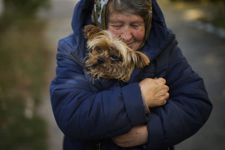 Una mujer calienta a su perro en Kivsharivka, Ucrania, el domingo 16 de octubre de 2022