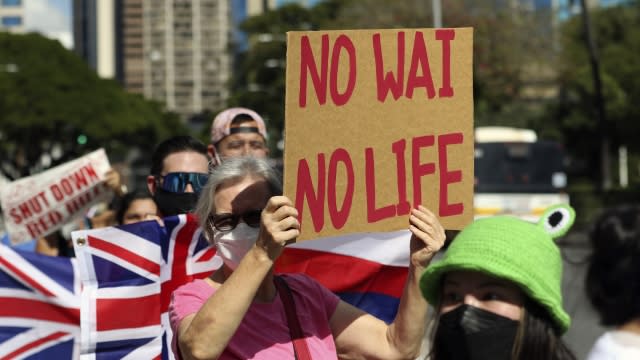 People hold signs in front of the Hawaii State Capitol during a rally calling for the closure of Red Hill