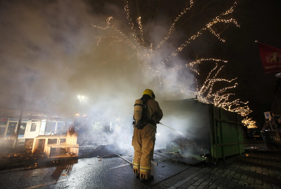 A firefighter extinguishes a a container that was set alight during protests against a nation-wide curfew in Rotterdam, Netherlands, Monday, Jan. 25, 2021. The Netherlands Saturday entered its toughest phase of anti-coronavirus restrictions to date, imposing a nationwide night-time curfew from 9 p.m. until 4:30 a.m. in a bid to control the COVID-19 infection rate. (AP Photo/Peter Dejong)