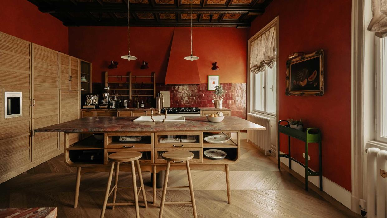  A kitchen with red walls and red marble countertops. 