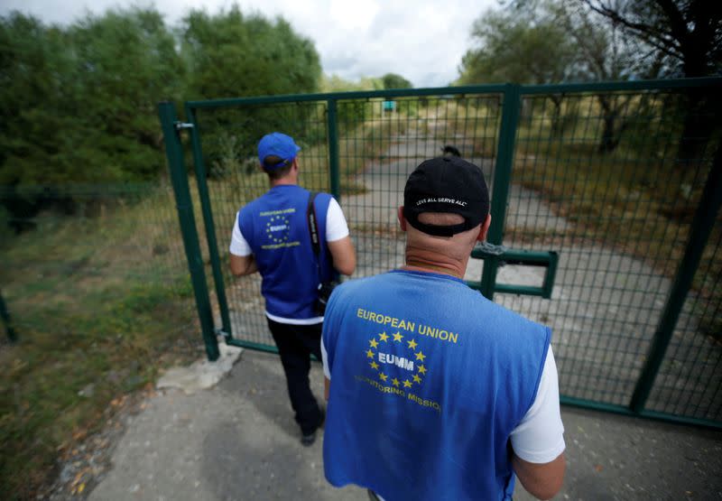 FILE PHOTO: Members of EUMM observe an area standing near the gate on the abandoned road at the de facto border of Georgia's breakaway region of South Ossetia in Ditsi