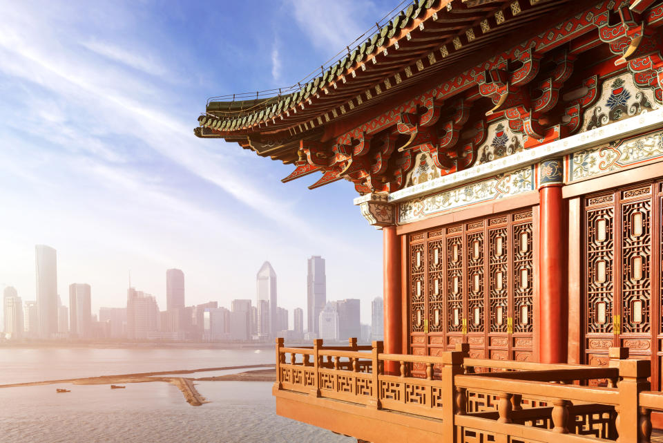 Close-up view of a traditional Chinese building with the skyline of a modern metropolis in the hazy distance.