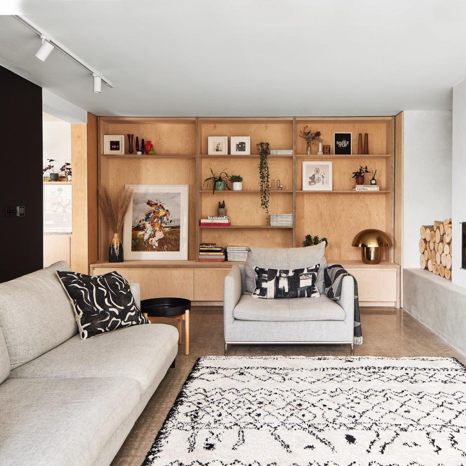 black and white fluffy rug in sitting area with grey seating and open shelving