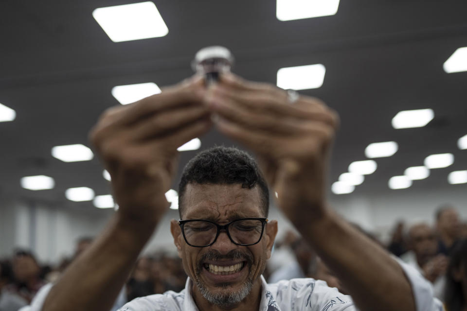 A man prays while raising a cup of wine during a political rally promoting evangelical electoral candidates, at a convention hall in Salvador, Brazil, Saturday, Sept. 17, 2022. Brazil’s President Jair Bolsonaro has been waging an all-out campaign to shore up the crucial evangelical vote ahead of Oct. 2 elections. Evangelicals helped carry him to power in 2018. (AP Photo/Rodrigo Abd)