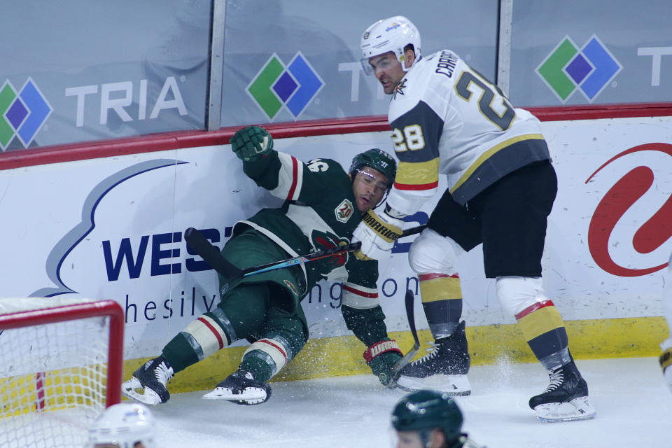 Vegas Golden Knights left wing William Carrier (28) takes down Minnesota Wild defenseman Jared Spurgeon (46) in the first period during an NHL hockey game, Monday, May 3, 2021, in St. Paul, Minn. (AP Photo/Andy Clayton-King)