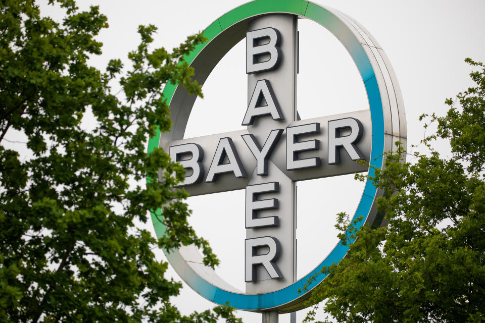 ARCHIV - 20.05.2019, Nordrhein-Westfalen, KÃ¶ln: Das Bayer Kreuz, Logo des Unternehmens Bayer, steht zwischen BÃ¤umen am Flughafen KÃ¶ln/Bonn. Bayer steuert im US-Rechtsstreit um angebliche Krebsrisiken von Glyphosat-Unkrautvernichtern laut einem US-Zeitungsbericht auf eine LÃ¶sung zu. Foto: Oliver Berg/dpa +++ dpa-Bildfunk +++