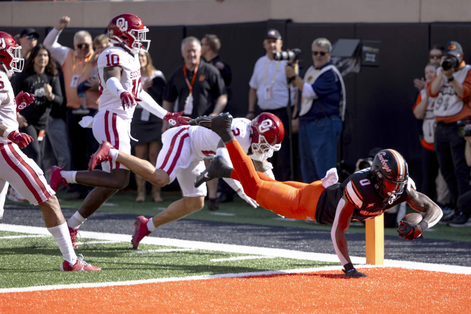 Oklahoma State running back Ollie Gordon II (0) dives into the engine past Oklahoma defensive back Billy Bowman Jr. (2) and linebacker Kip Lewis (10) in the first half of an NCAA college football game Saturday, Nov. 4, 2023, in Stillwater, Okla. (AP Photo/Mitch Alcala)