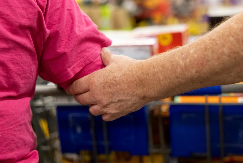 Jerry House holds onto Dannine's arm for guidance at Sam's Club on Jan. 17, 2024. As they walk, Dannine makes sure to lead House around the store as they get snacks for House's vending machines.
