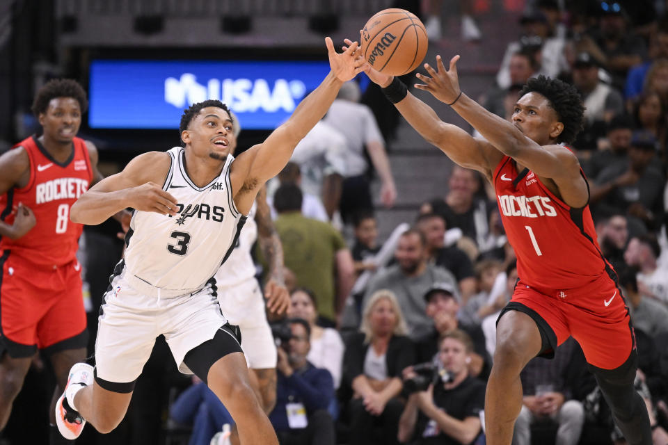 San Antonio Spurs' Keldon Johnson (3) and Houston Rockets' Amen Thompson chase the ball during the second half of a preseason NBA basketball game, Wednesday, Oct. 18, 2023, in San Antonio. San Antonio won 117-103. (AP Photo/Darren Abate)