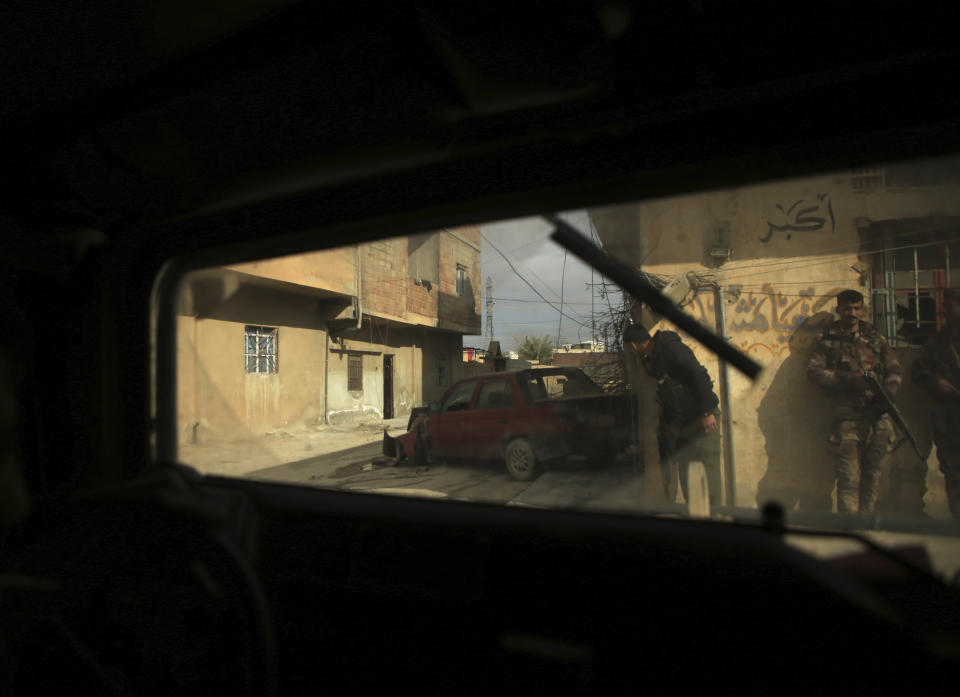 Kurdish-led Syrian Democratic Forces fighters, take their positions at an alley near Gweiran Prison, in Hassakeh, northeast Syria, Sunday, Jan. 23, 2022. Clashes between U.S.-backed Syrian Kurdish fighters and militants continued for a fourth day Sunday near a prison in northeastern Syria that houses thousands of members of the Islamic State group, the Kurdish force said. (AP Photo/Hogir Al Abdo)