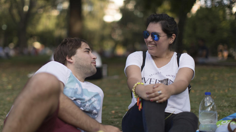 Tomas Ruiz talks with his friend Maria Julia Zuccotti as they hang out with friends at Las Heras Park in Buenos Aires, Argentina, Tuesday, April 2, 2019, two days before he flew to Ireland in search of work. Academics, research groups and consulting firms agree there has been a rise in the number of people leaving, especially among young, educated Argentines, just as there was during the nation's worst crisis 17 years ago. (AP Photo/Tomas F. Cuesta)
