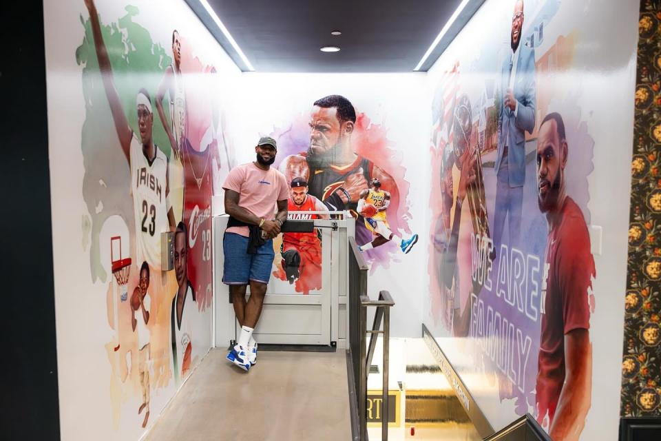 LeBron James is shown with the murals created by Stark County artist Dirk Rozich at the entrance to the LeBron James' Home Court museum, which is housed on the lower level of House Three Thirty in Akron.