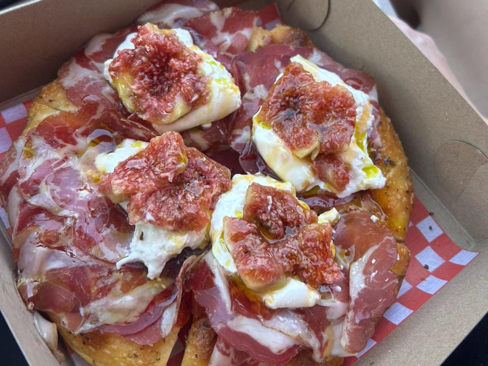 box of focaccia pizza with cheese, figs, and ham