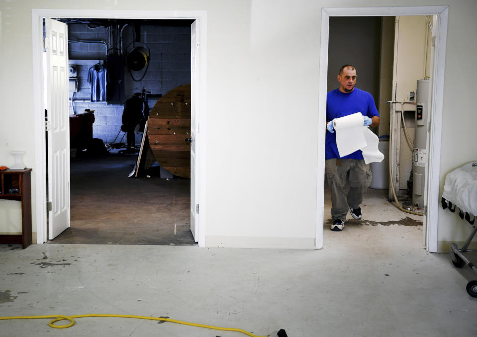 In this Wednesday, Aug. 11, 2021, photo, employee Chris Olachia walks through The Natural Funeral's human body composting facility in Arvada, Colo. On Sept. 7, Colorado became the second state after Washington to allow human body composting, and Oregon will allow the practice beginning next July. Vessels will be packed with wood chips and straw and will be able to compost a body in six months. (AP Photo/Thomas Peipert)