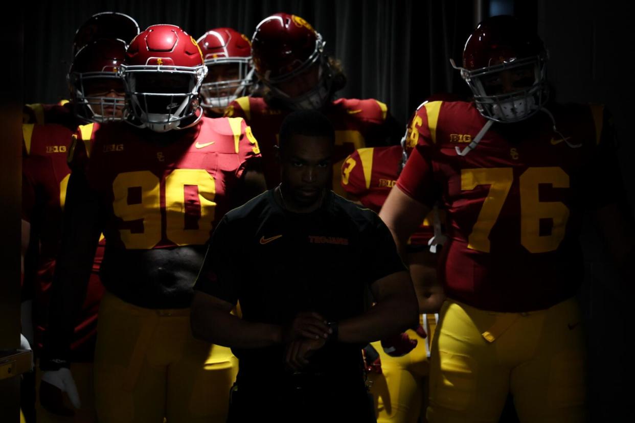 USC Trojans make their way through darkness and scattered rays of light onto the field before the game