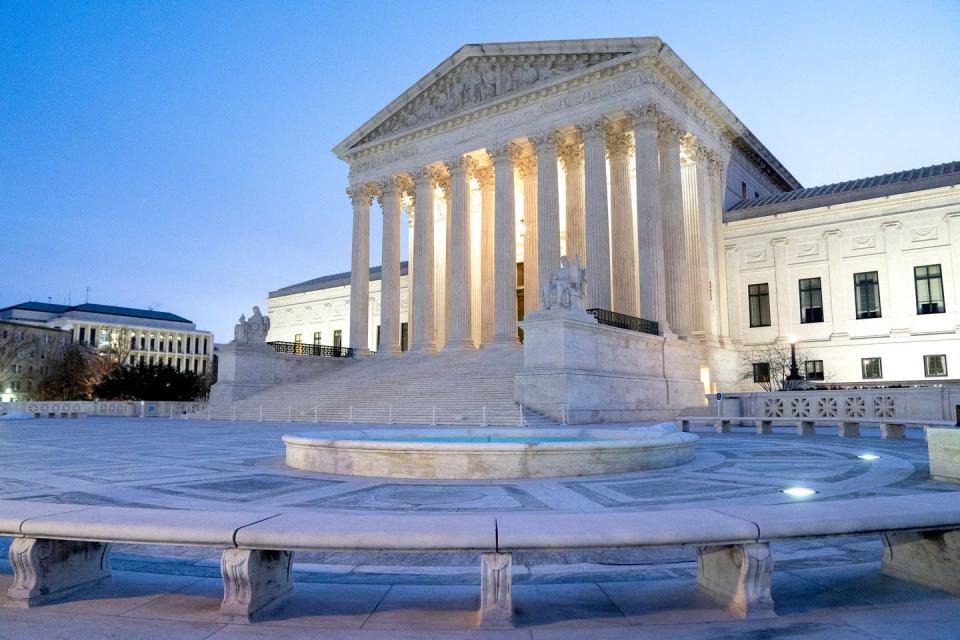 The Supreme Court building, lit up with a blue sky behind it.