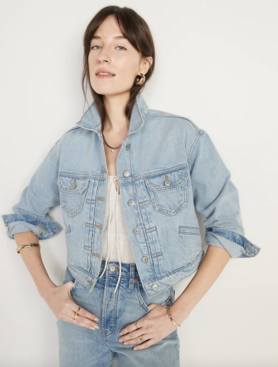 brunette model in blue jeans and blue denim Cropped Jean Jacket (Photo via Old Navy)