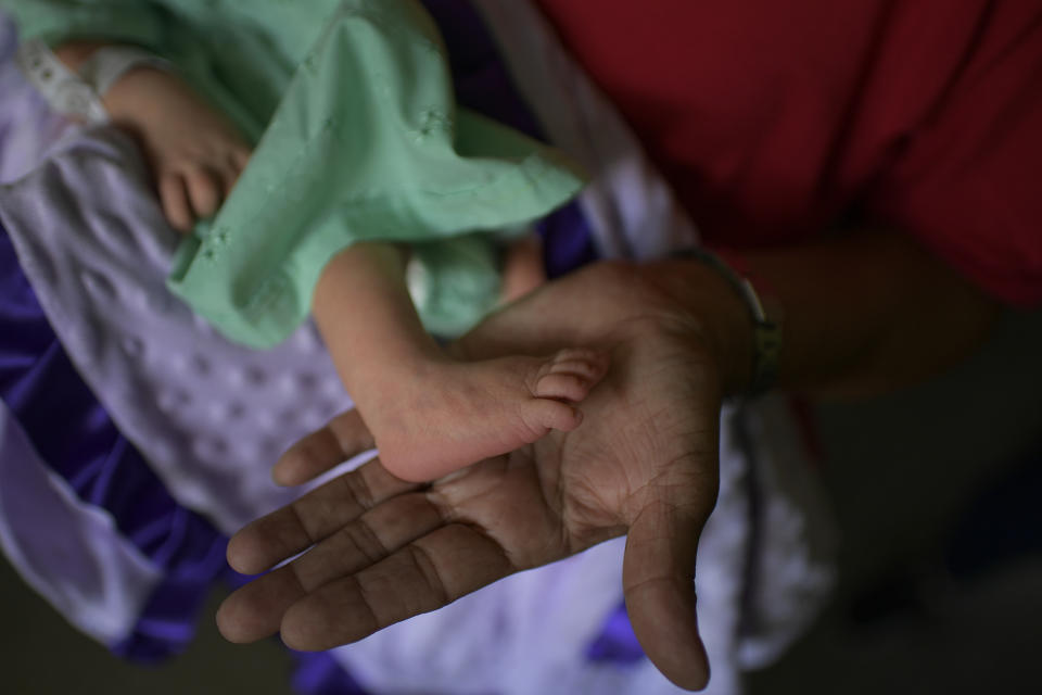 Nelida López sostiene el pie de Peyton, su nieta recién nacida, el día que Peyton llegó a casa desde el hospital, en el barrio de Catia de Caracas, Venezuela, el sábado 12 de septiembre de 2020. (AP Foto/Matias Delacroix)