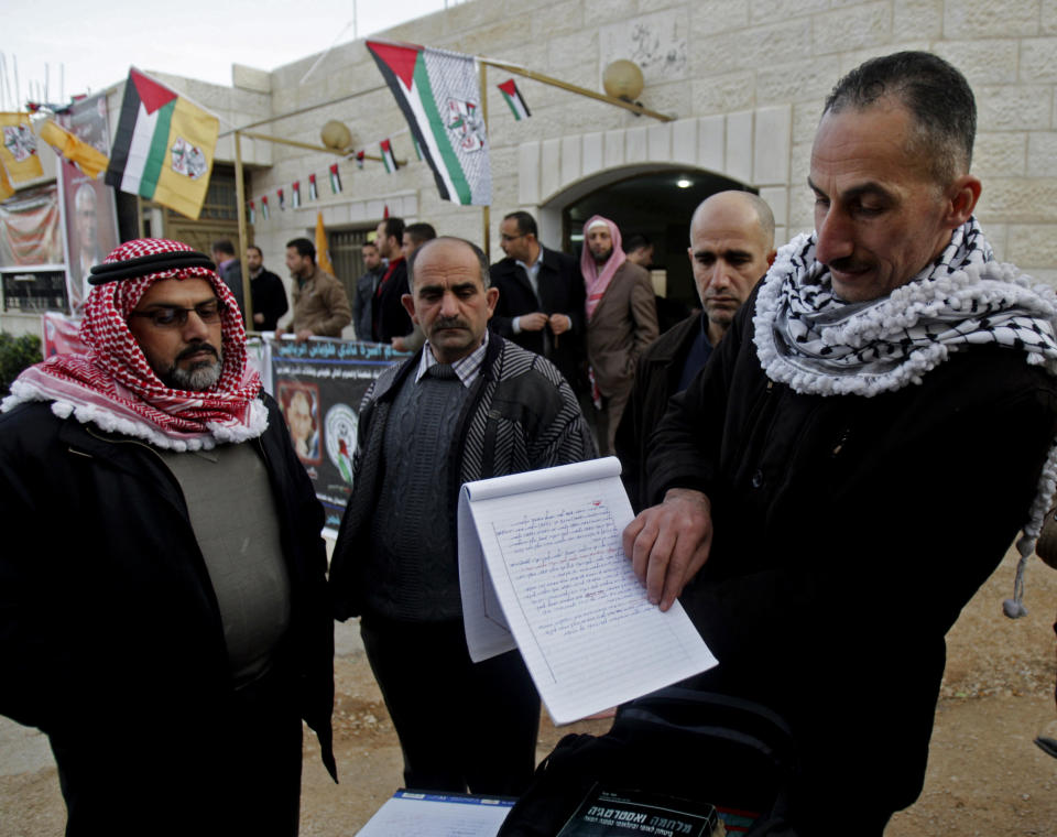 In this Friday, Jan. 3, 2014 photo, Jamal Abu Muhsin, second right, who is among hundreds of Palestinians having spent their time in Israeli prisons pursuing an education and was recently released, shows his university degree earned at an Israeli prison in the West Bank town of Tubas near Jenin. Abu Muhsin spent his time in prison pursuing an education _ a program that has been praised by Palestinians but has caused a stir with Israelis who believe that murderers are being undeservedly coddled. "When I found myself in jail for life, I was faced with two options: either I make meaning for my life or waste my life and my mind behind bars," said Abu Muhsin, now 42, from his home in the West Bank city of Tubas. (AP Photo/Nasser Ishtayeh)