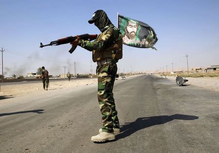 A fighter from the Shi'ite Badr Brigade militia wears a religious flag as he guards a checkpoint recently taken from militants of the Islamic State outside the town of Amerli, in this September 5, 2014 file photo. REUTERS/Ahmed Jadallah/Files