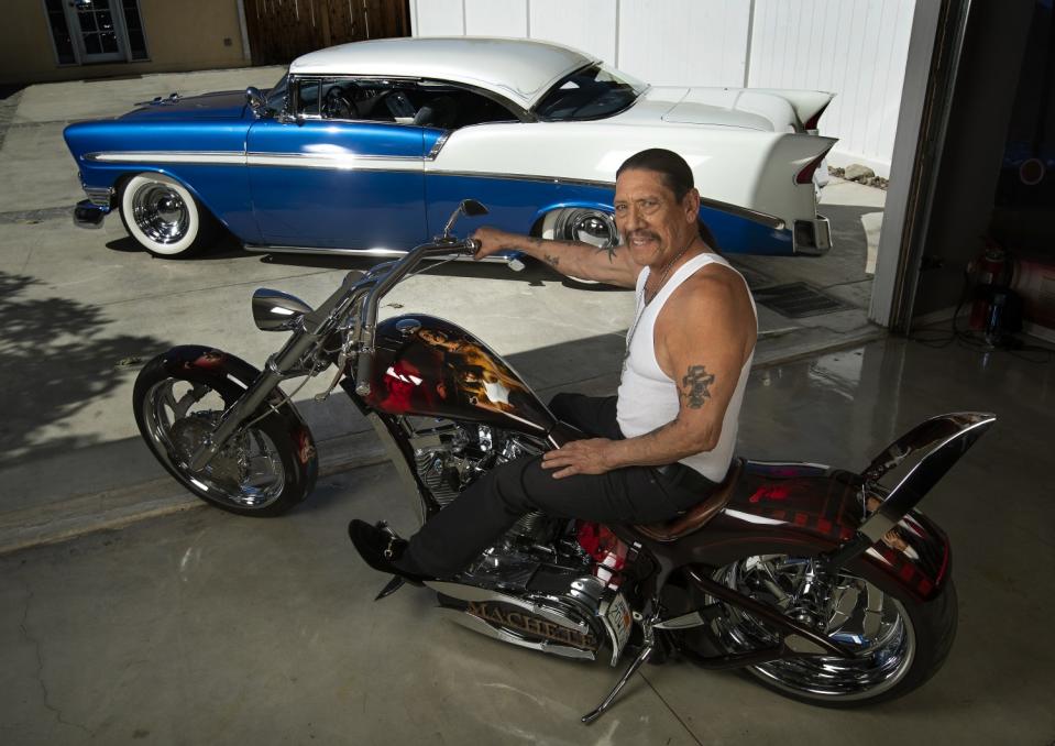 Danny Trejo on a Harley-Davidson motorcycle near a 1956 blue and white Chevrolet Bel Air automobile