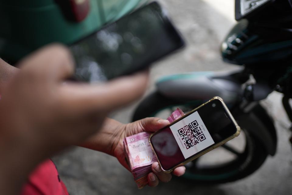 A workers scans a QR code at a fuel station in Colombo, Sri Lanka, Wednesday, March 29, 2023. Sri Lanka’s government has announced reduction in fuel prices, the first significant relief to the public after a year of shortages and skyrocketing prices amid the country’s worst economic crisis. (AP Photo/Eranga Jayawardena)