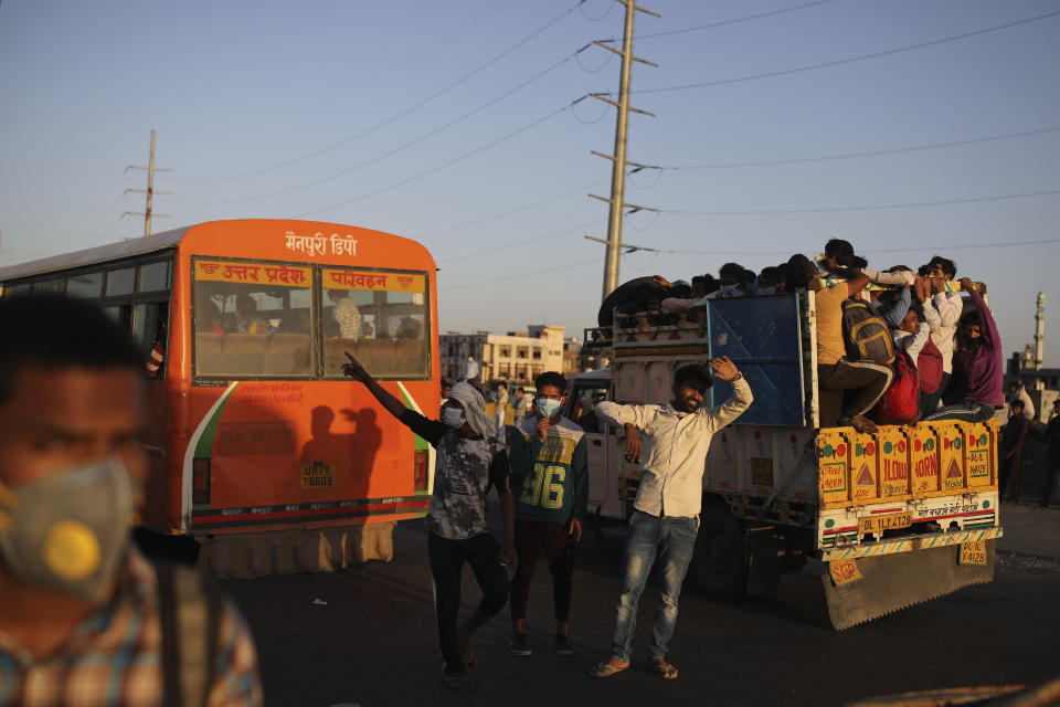 In this Saturday, March 28, 2020, file photo, Indian men try to stop vehicles for migrant workers waiting for transportation to their respective villages following a lockdown amid concern over spread of coronavirus in New Delhi, India. Over the past week, India’s migrant workers - the mainstay of the country’s labor force - spilled out of big cities that have been shuttered due to the coronavirus and returned to their villages, sparking fears that the virus could spread to the countryside. It was an exodus unlike anything seen in India since the 1947 Partition, when British colothe subcontinent, with the 21-day lockdown leaving millions of migrants with no choice but to return to their home villages. (AP Photo/Altaf Qadri, File)