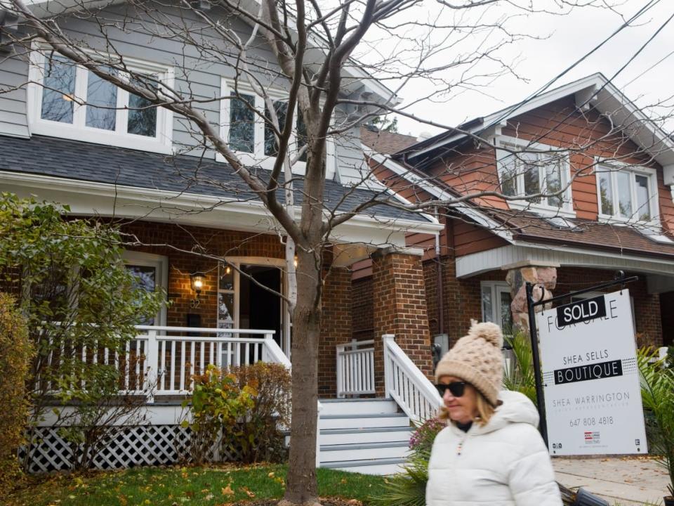 A sold sign hangs in front of a house in Toronto in November. Sales volumes and selling prices were sharply lower during the month. (Showwei Chu/CBC - image credit)