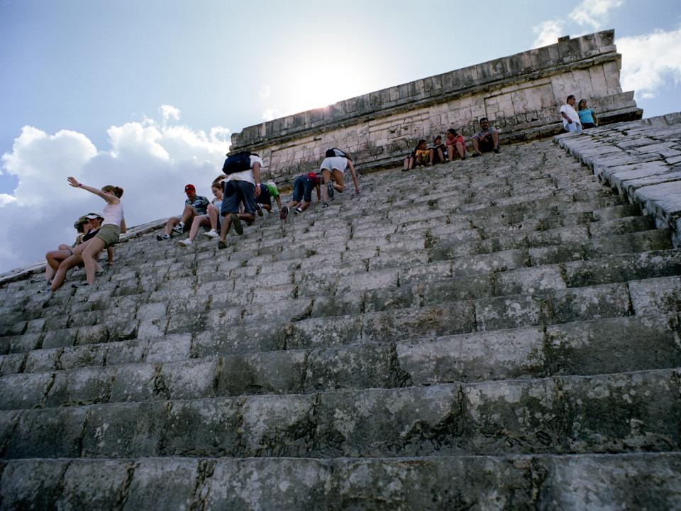 Tourists climbing the Temple of Kukulcan, a pyramid at the center of the center of the Chichen Itza archaeological site, in 2004.